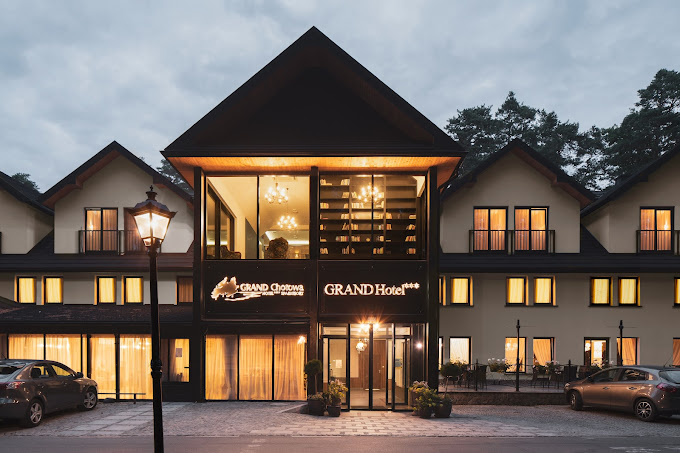 Główne wejście do Grand Chotowa Hotel – nowoczesna fasada z podświetlonym wnętrzem i szyldem hotelu